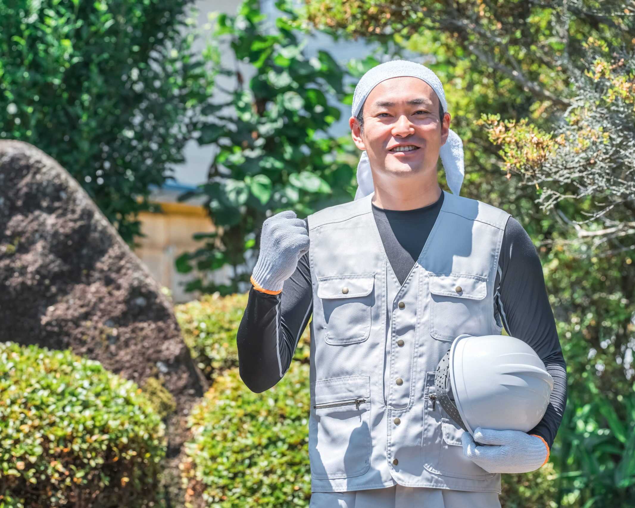 庭で道具を持つ作業着姿の男性